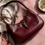 Borsa a spalla senza marchi in pelle bordeaux su tessuto rosa con un foulard