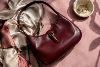 Borsa a spalla senza marchi in pelle bordeaux su tessuto rosa con un foulard